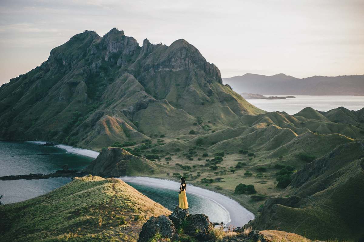 mountain range woman standing on mountain near body of water mountain